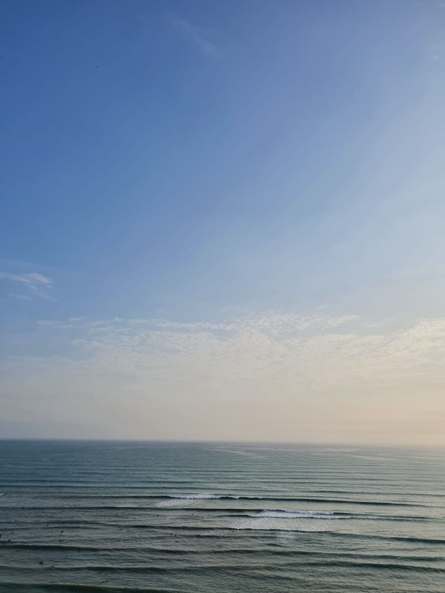 A calm sea under a pale, wide sky.